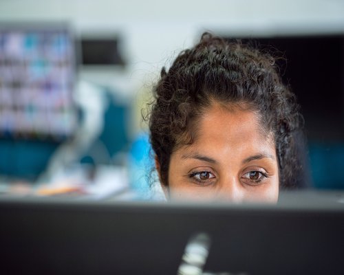 A person working focused at a bright office desk in Jakarta